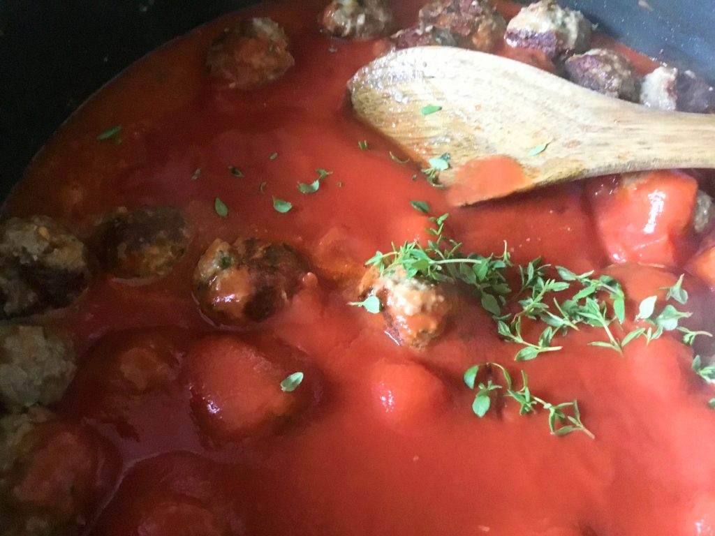 Low FODMAP beef meatballs stewing in a tomato sauce