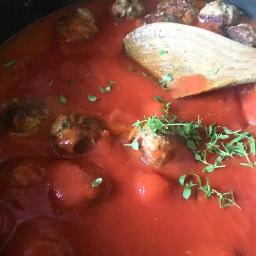 Low FODMAP beef meatballs stewing in a tomato sauce
